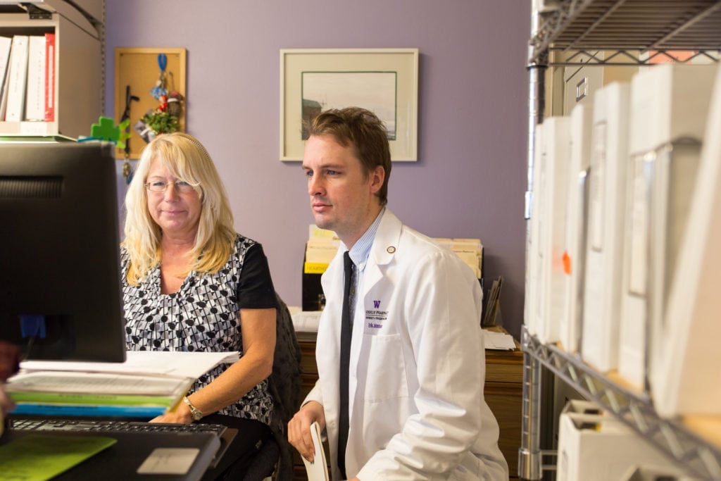 UW Pharmacy alum Erik Johnsen reviews a patient's electronic health records with a colleague.