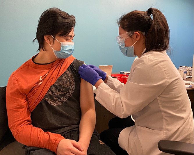 A graduate student administers the COVID-19 vaccine