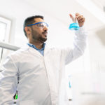 man in lab coat holding a glass bottle